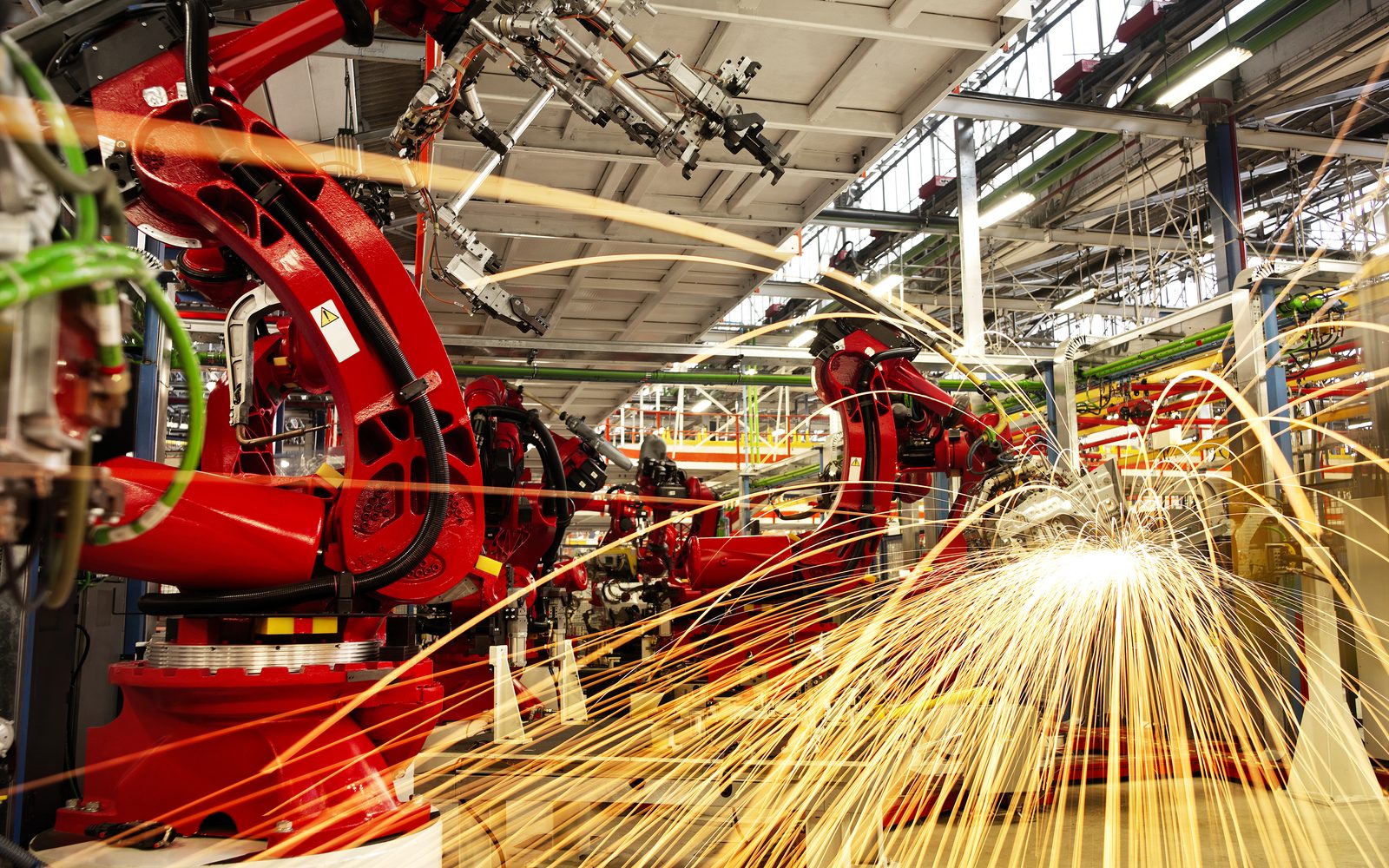 Red welding robots throwing sparks on an automotive assembly line